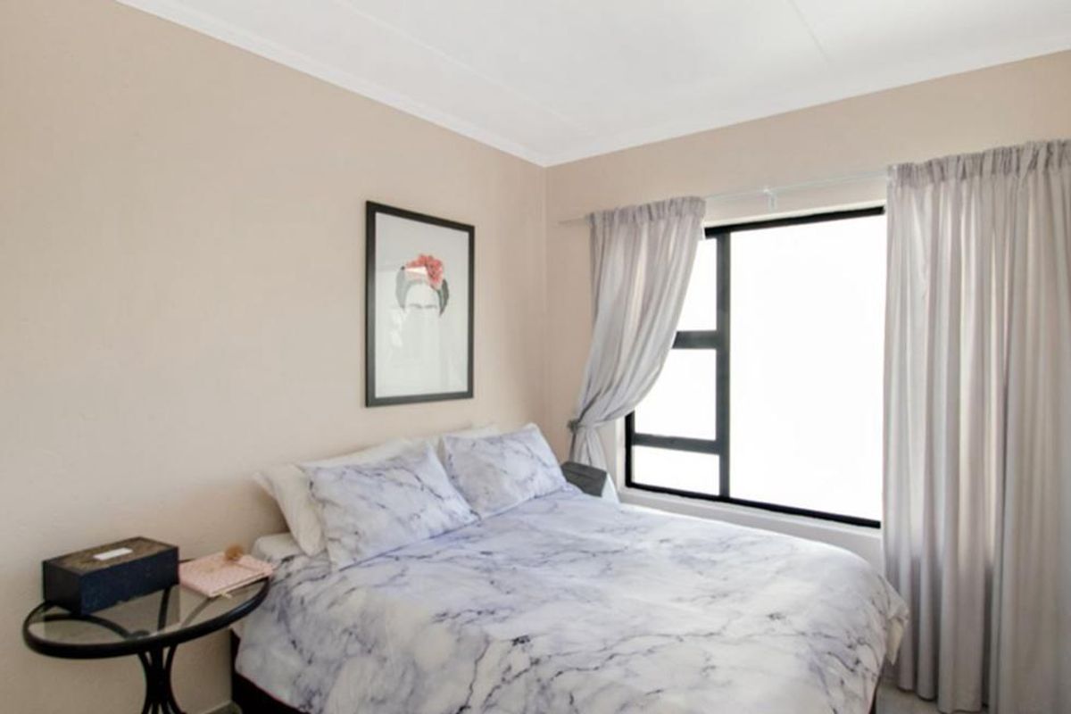 A well-maintained bedroom featuring neutral wall tones and a large window with fitted curtain tracks.