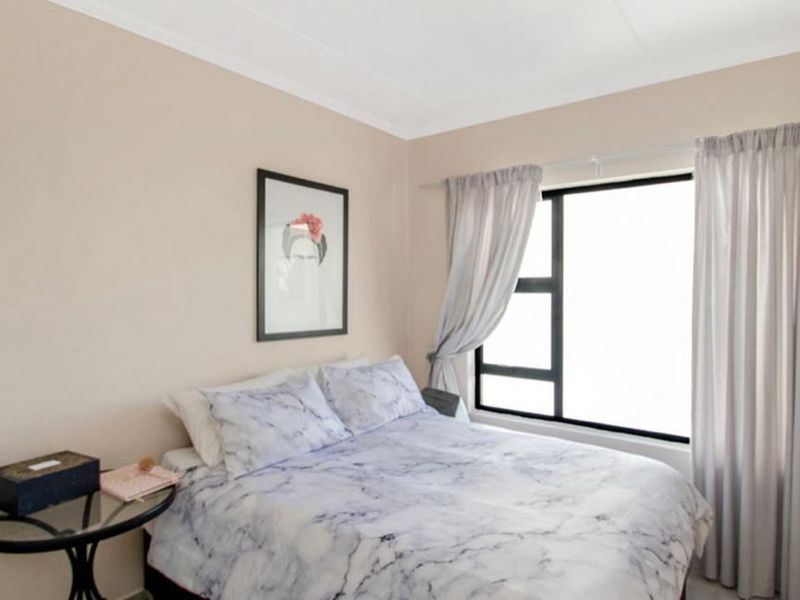 A well-maintained bedroom featuring neutral wall tones and a large window with fitted curtain tracks.