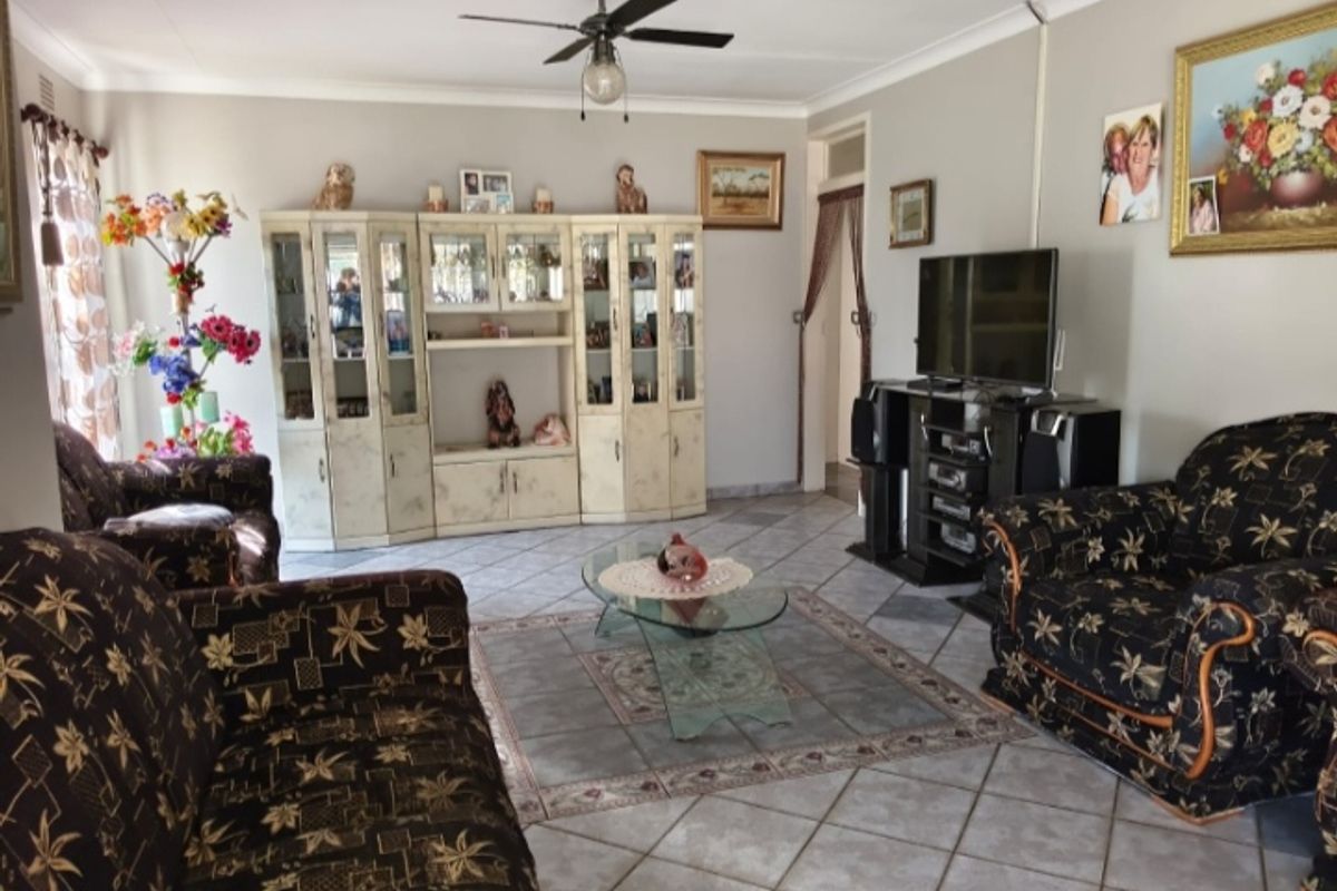 A spacious living room featuring ceramic floor tiles, a ceiling fan, and built-in display cabinetry, offering a functional and comfortable living space.