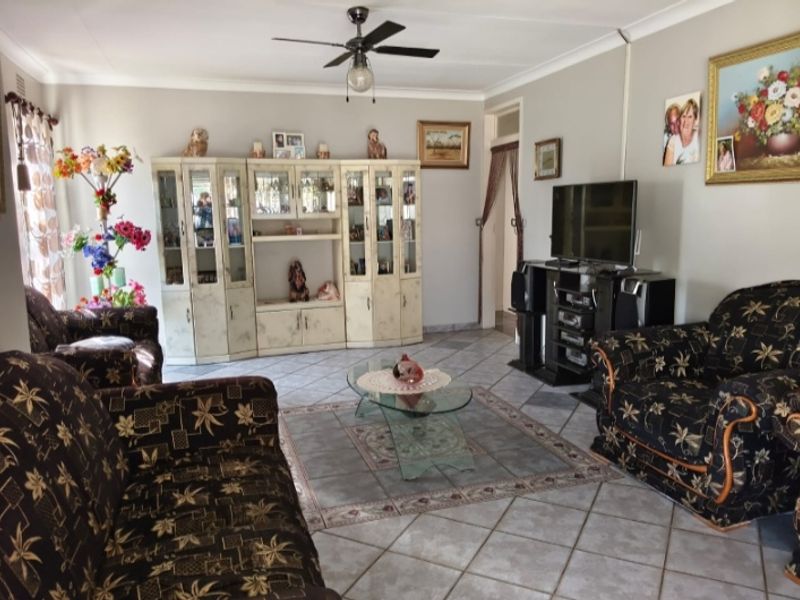 A spacious living room featuring ceramic floor tiles, a ceiling fan, and built-in display cabinetry, offering a functional and comfortable living space.
