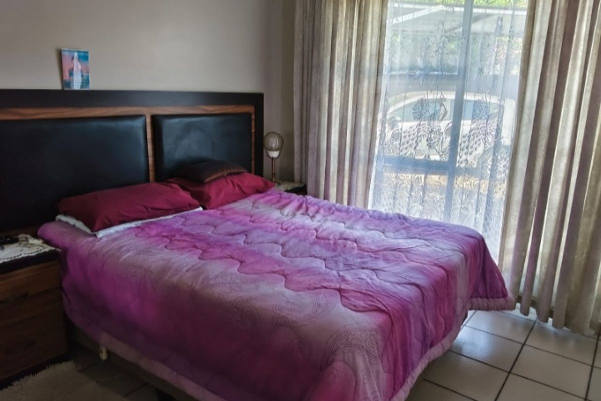 A bedroom featuring tiled flooring and a large window allowing natural light, providing a functional space for rest.
