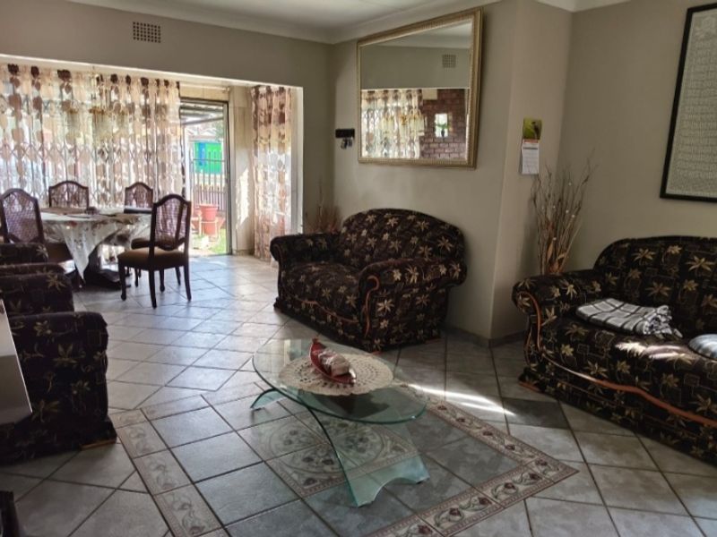 Open plan living and dining area featuring ceramic floor tiles and direct access to the rear garden through a sliding security gate.