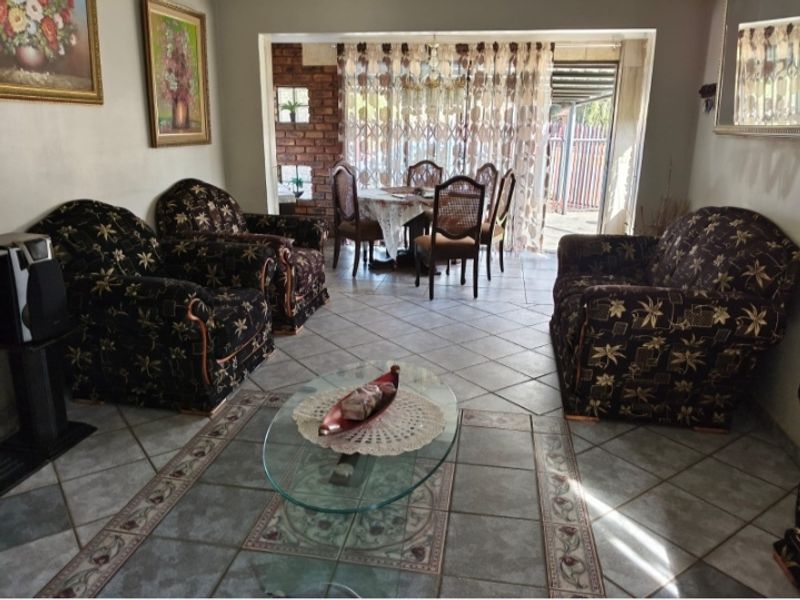 Open plan living and dining area featuring tiled flooring, exposed brick accents, and a sliding glass door leading to the outdoor space.