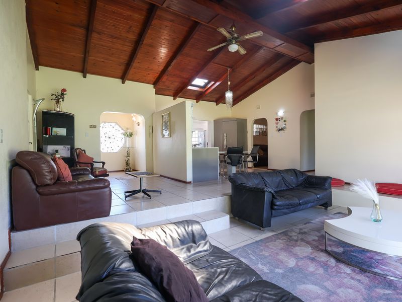 Spacious open-plan living area featuring a high exposed timber beam ceiling, skylight, and split-level tiled flooring with a distinct transition between living zones.