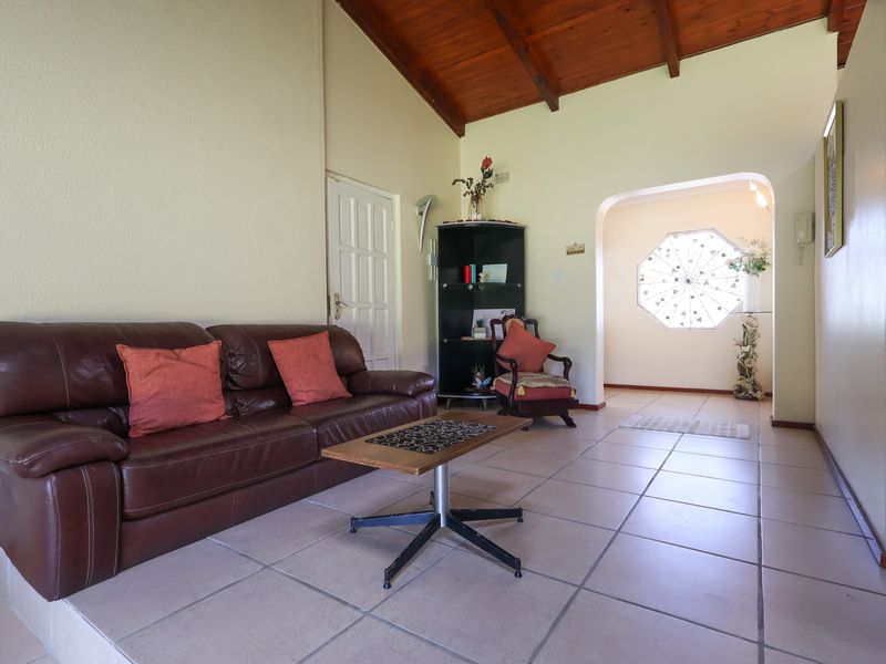 Spacious living area featuring high exposed timber rafter ceilings, ceramic floor tiles, and a unique decorative octagonal window in the adjacent hallway.