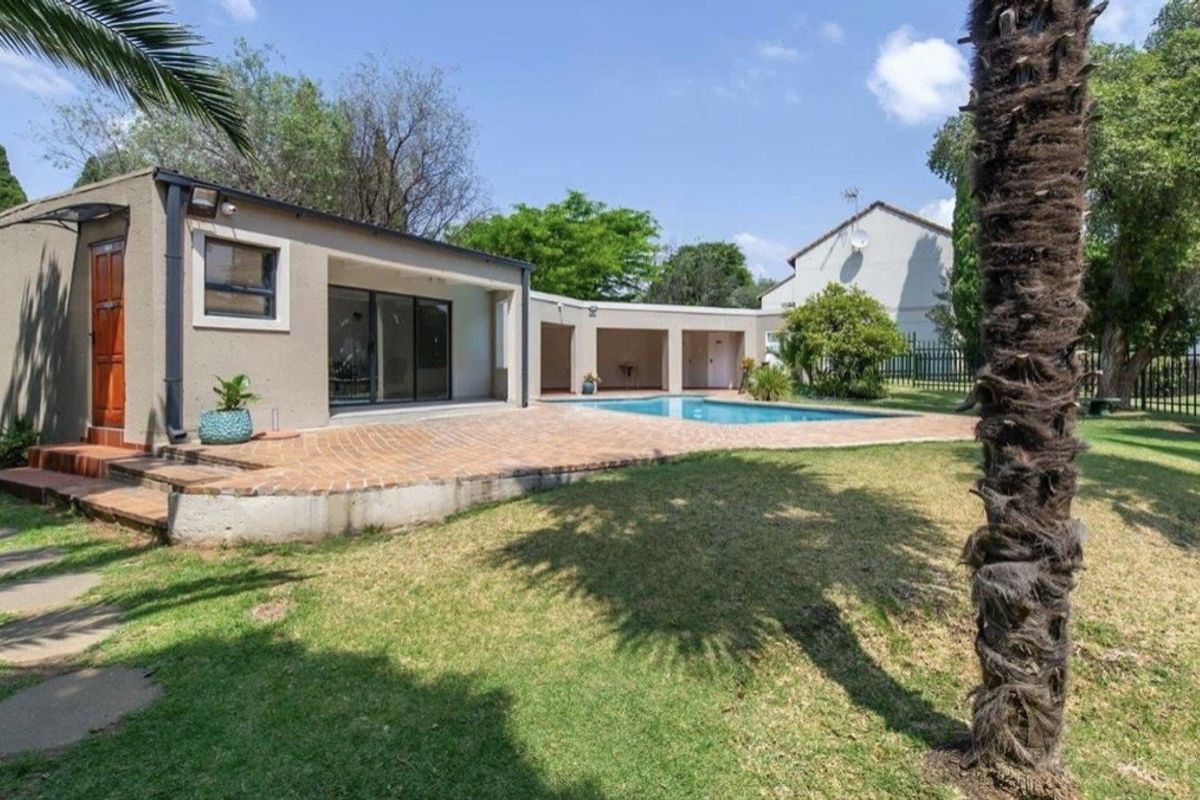 A spacious rear garden featuring a swimming pool, brick-paved patio area, and a built-in braai, perfect for outdoor entertaining.