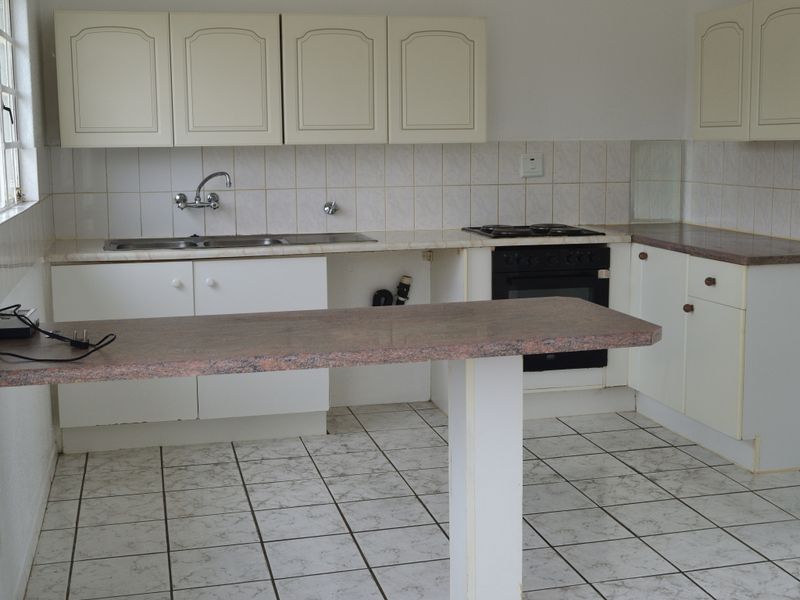 Functional kitchen featuring laminate countertops, built-in oven, gas hob, double basin sink, and ample cabinetry with a breakfast bar.