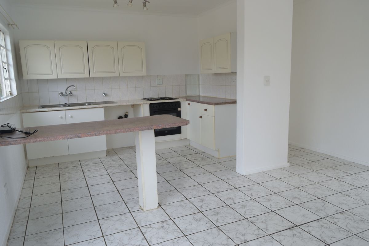 An empty kitchen featuring tiled flooring, laminate countertops, built-in cabinetry, and a gas hob with oven, offering a functional space ready for renovation.