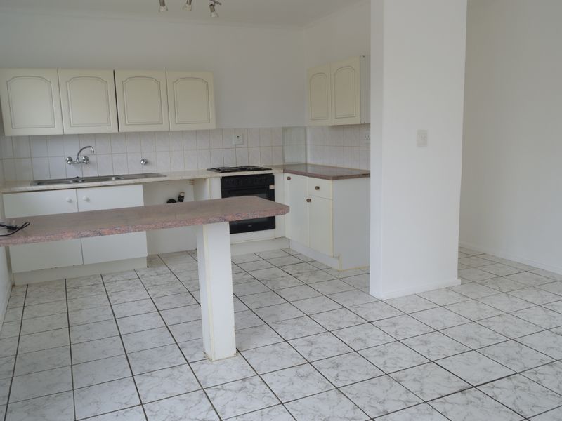 An empty kitchen featuring tiled flooring, laminate countertops, built-in cabinetry, and a gas hob with oven, offering a functional space ready for renovation.