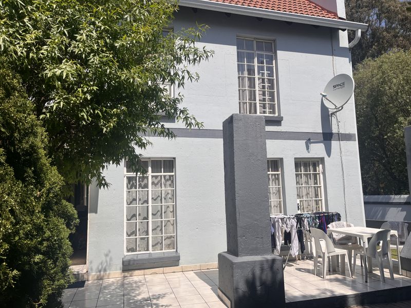 Rear exterior view of the townhouse featuring a tiled patio area, multi-pane windows, and a satellite dish installation.