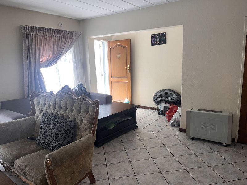 A living room area featuring tiled flooring and a wall-mounted panel heater, providing a functional space with direct access to an exterior door.