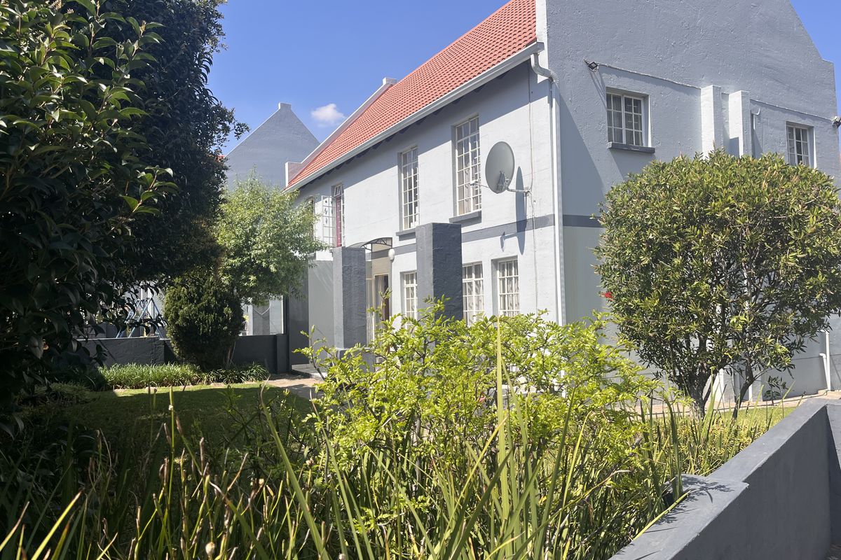 A view of the rear elevation of the townhouse, featuring a terracotta tiled roof, multi-pane windows, and a well-maintained garden area.