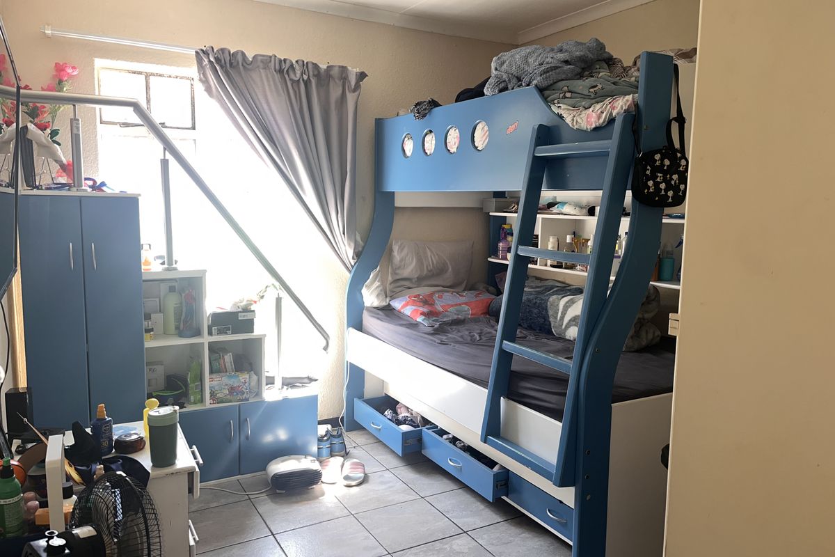 A bedroom featuring tiled flooring and a window, currently utilized as a children's room.