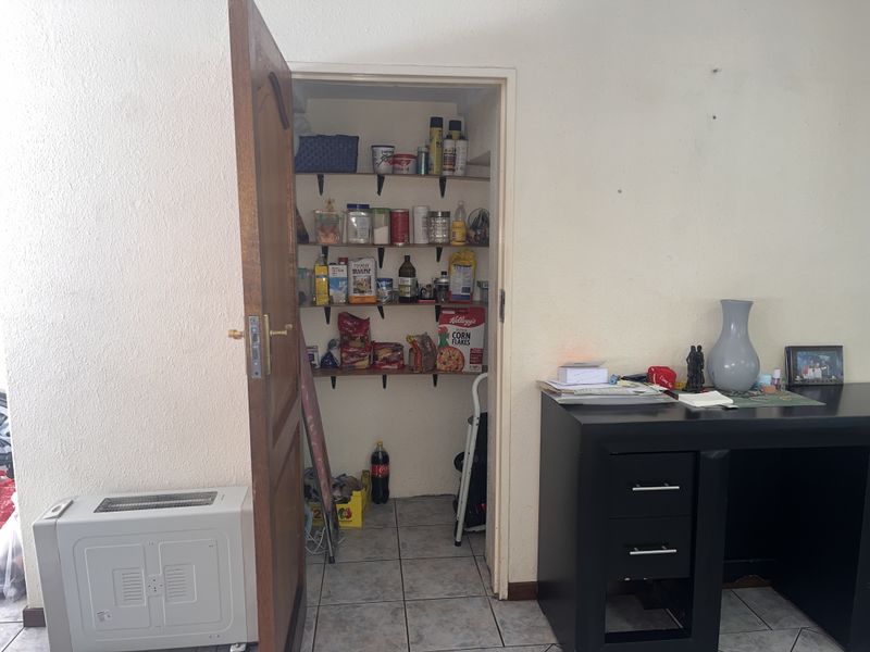 A functional walk-in pantry or scullery area featuring built-in shelving and tiled flooring, providing convenient additional storage space.