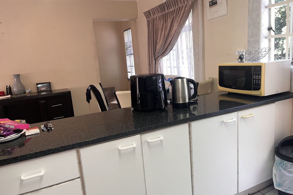 Kitchen area featuring white cabinetry, dark granite countertops, and tiled flooring, offering a functional layout with potential for modern updates.
