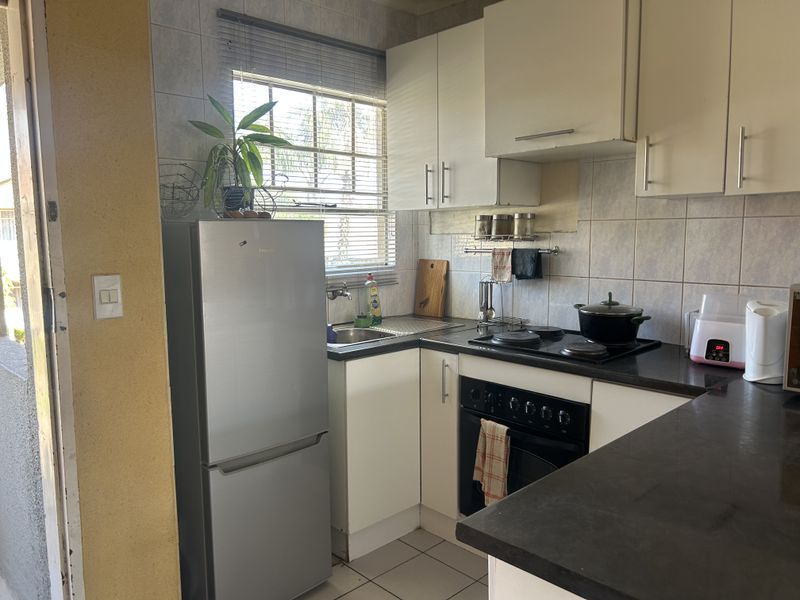 Compact kitchen featuring built-in cabinetry, laminate countertops, an electric hob, and an integrated oven with tiled backsplash and flooring.