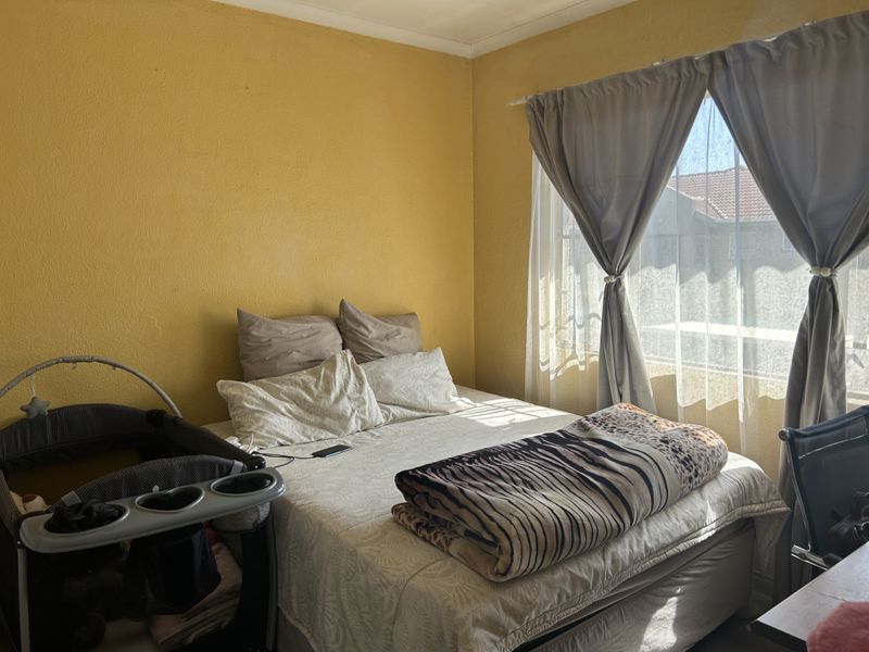 A bedroom featuring yellow walls and natural light from a window with installed curtain rails.