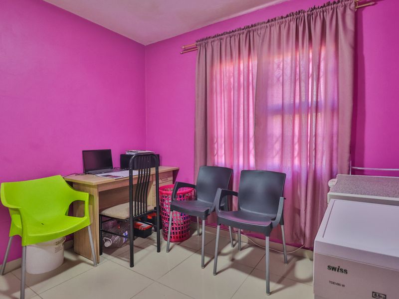 A bedroom featuring tiled flooring and a window with a curtain rod, currently utilized as a multi-purpose space.