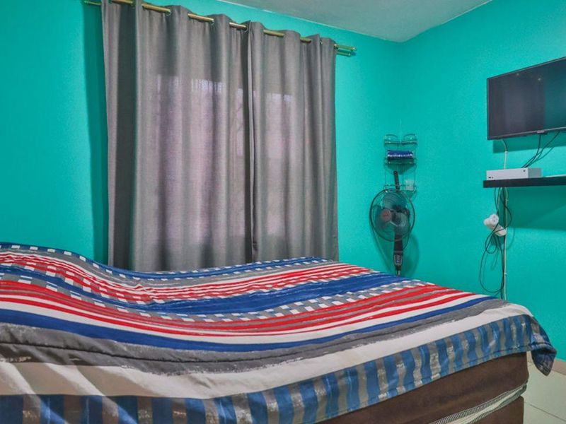 A bedroom featuring tiled flooring and a window with curtain rod, currently painted in a vibrant teal color.