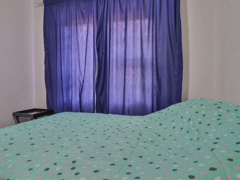 A simple bedroom featuring a window with curtains.