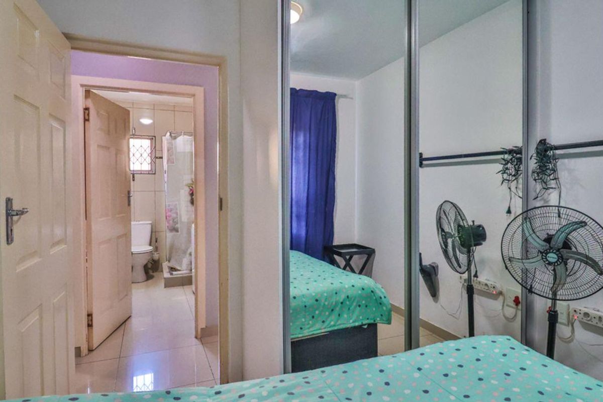 A bedroom featuring built-in mirrored wardrobes and tiled flooring, with direct access to an en-suite bathroom.