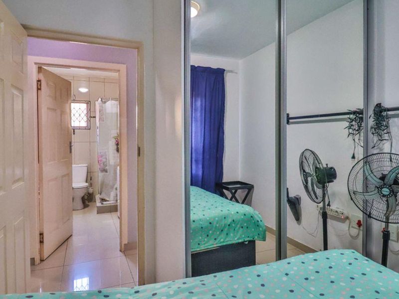 A bedroom featuring built-in mirrored wardrobes and tiled flooring, with direct access to an en-suite bathroom.