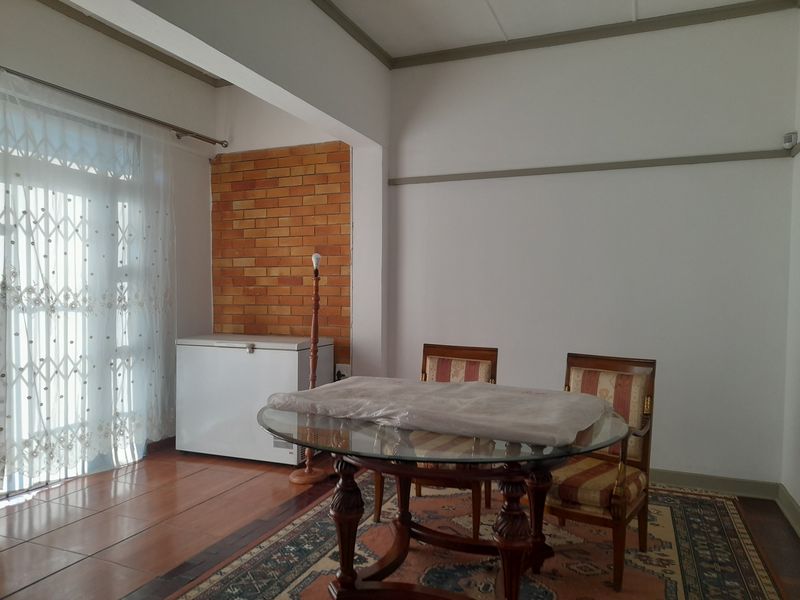Dining area featuring an exposed brick accent wall, tiled flooring, and a sliding glass door providing access to the exterior.