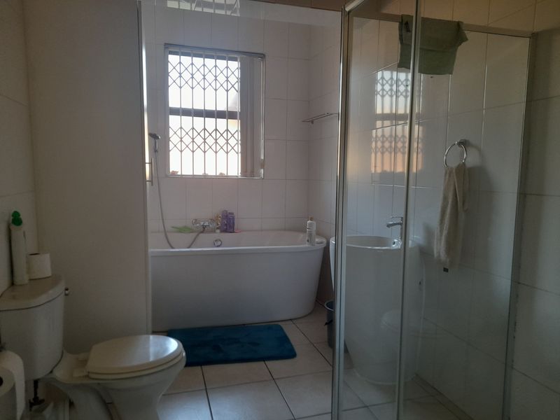 A functional bathroom featuring a freestanding bathtub, a separate glass-enclosed shower, a pedestal basin, and a toilet with tiled finishes throughout.
