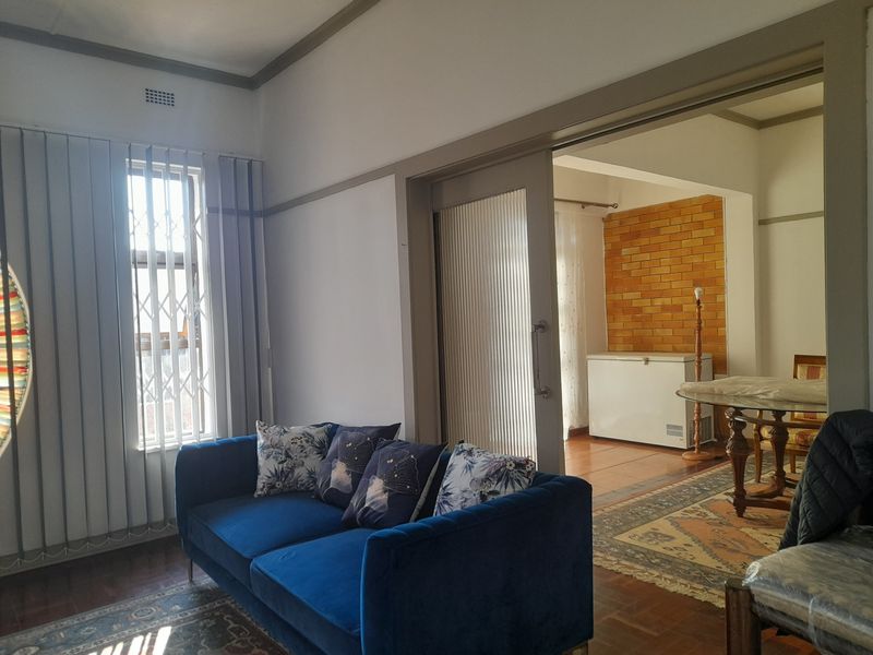 A living room featuring parquet flooring and a sliding door leading to an adjacent space with an exposed brick wall feature.