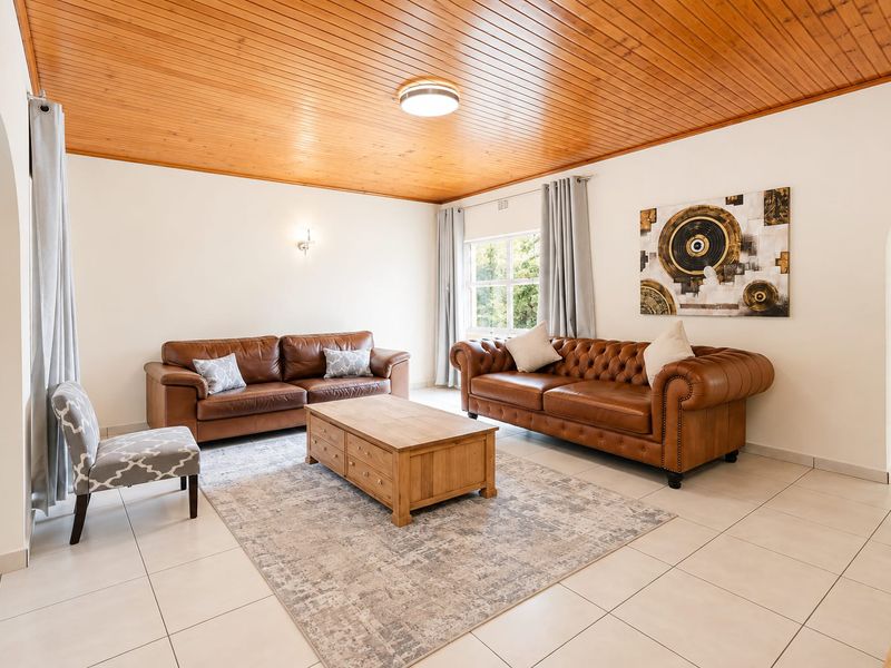 Spacious living room featuring a warm timber tongue and groove ceiling, neutral tiled flooring, and classic archway architectural details.