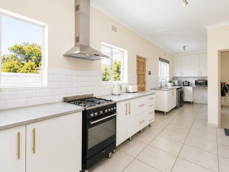 Modern kitchen featuring white cabinetry, stone countertops, subway tile backsplash, and a stainless steel gas stove with extractor fan.