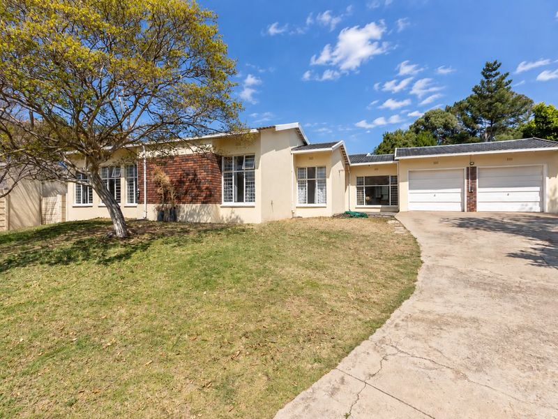 Front exterior view of a single-story house featuring a double garage, concrete driveway, and a spacious front lawn.