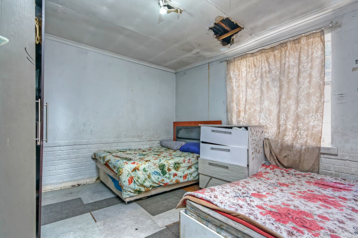 A bedroom featuring exposed brickwork and a built-in wardrobe, currently requiring significant ceiling and wall repairs to restore the space.