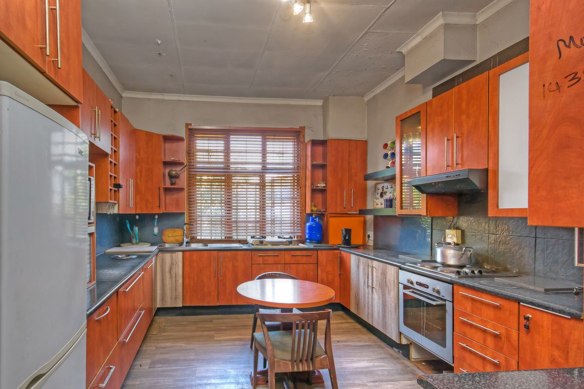 A dated kitchen featuring wood-look cabinetry, laminate countertops, and integrated appliances, requiring cosmetic updates to improve the overall aesthetic and condition.