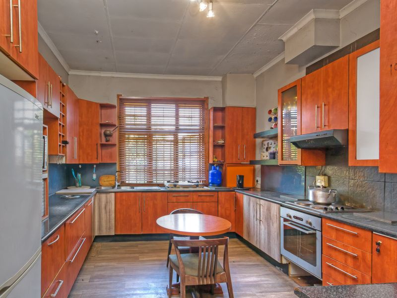 A dated kitchen featuring wood-look cabinetry, laminate countertops, and integrated appliances, requiring cosmetic updates to improve the overall aesthetic and condition.