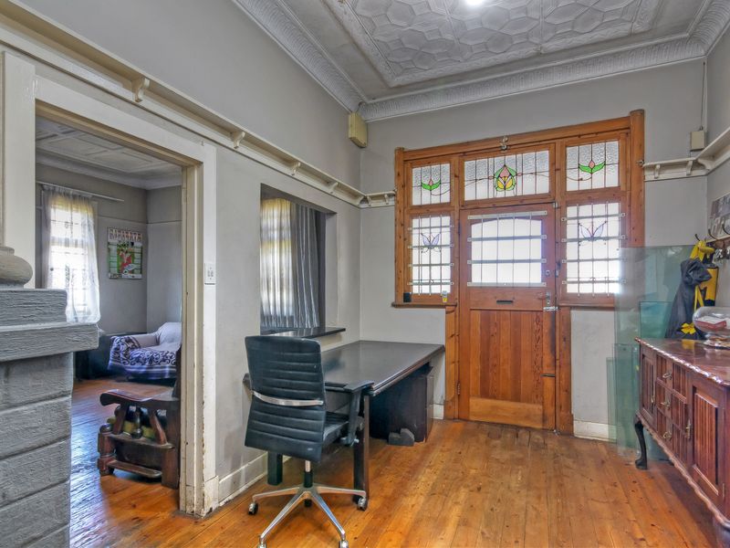 Entrance hall featuring original timber flooring, decorative pressed metal ceilings, and a character-filled stained glass timber front door.