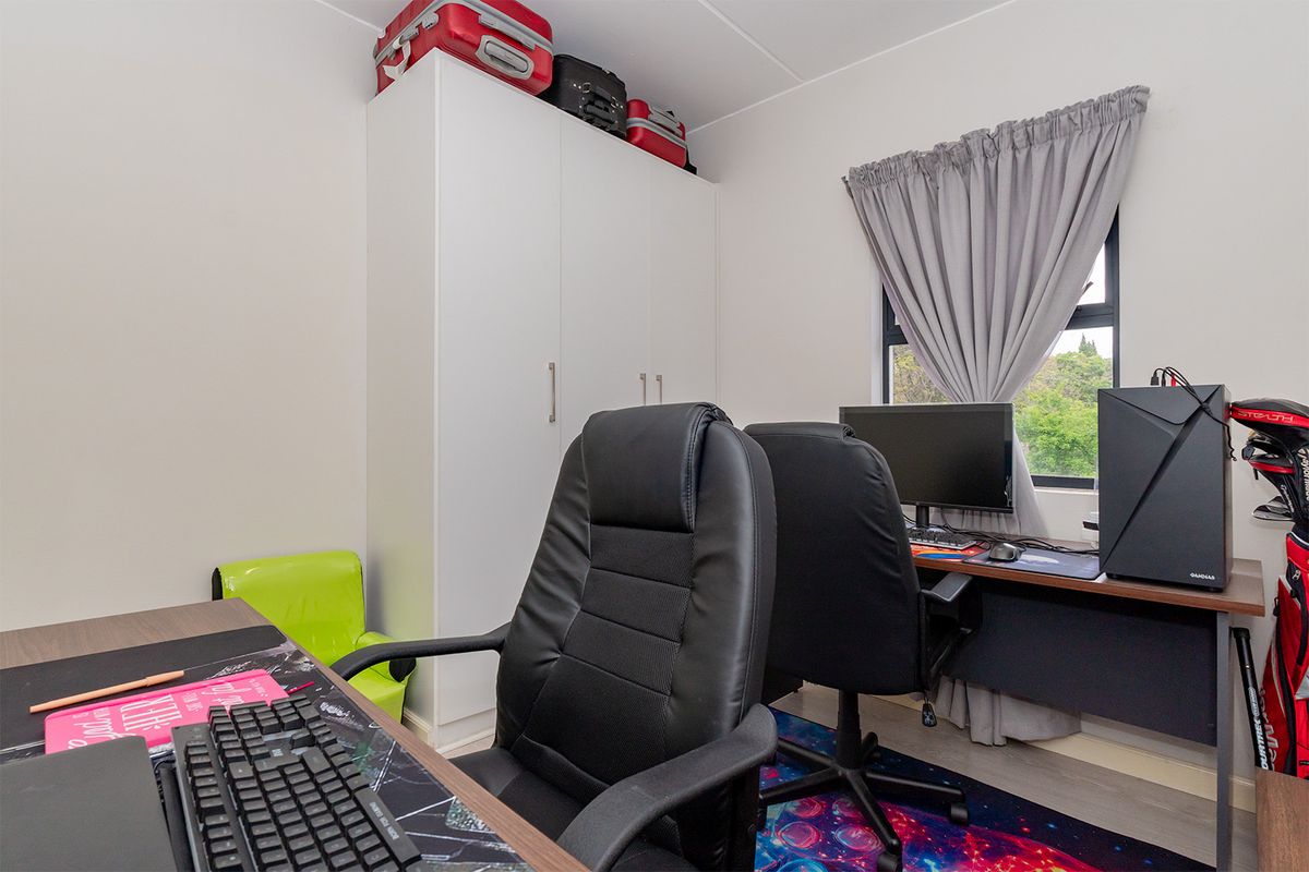 A functional bedroom featuring a built-in wardrobe and a window, currently utilized as a home office space.