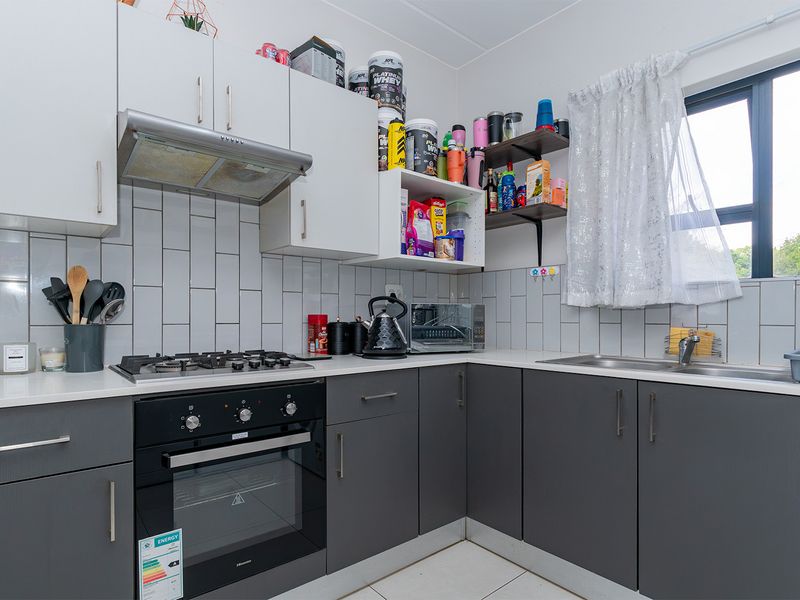 Modern kitchen featuring dark grey lower cabinetry, white upper cabinets, subway tile backsplash, built-in oven, gas hob, and stainless steel sink.