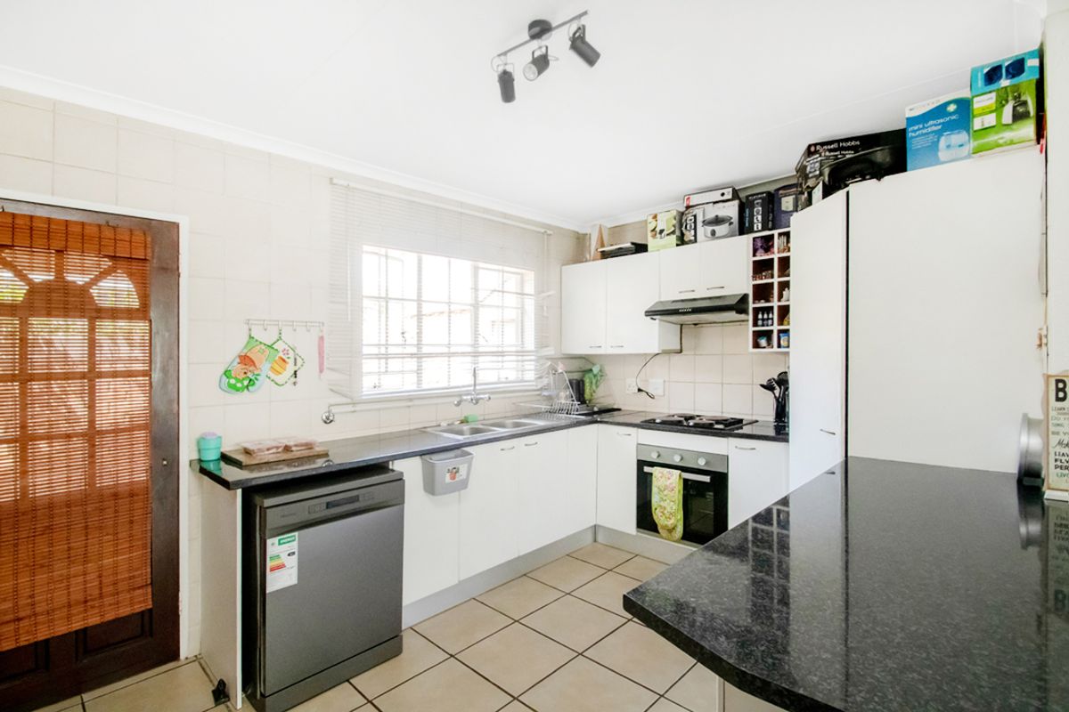Functional kitchen featuring granite countertops, built-in oven, gas hob, extractor fan, and tiled flooring with direct access to the exterior.