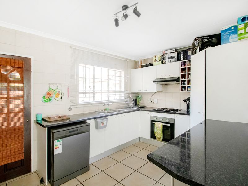 Functional kitchen featuring granite countertops, built-in oven, gas hob, extractor fan, and tiled flooring with direct access to the exterior.