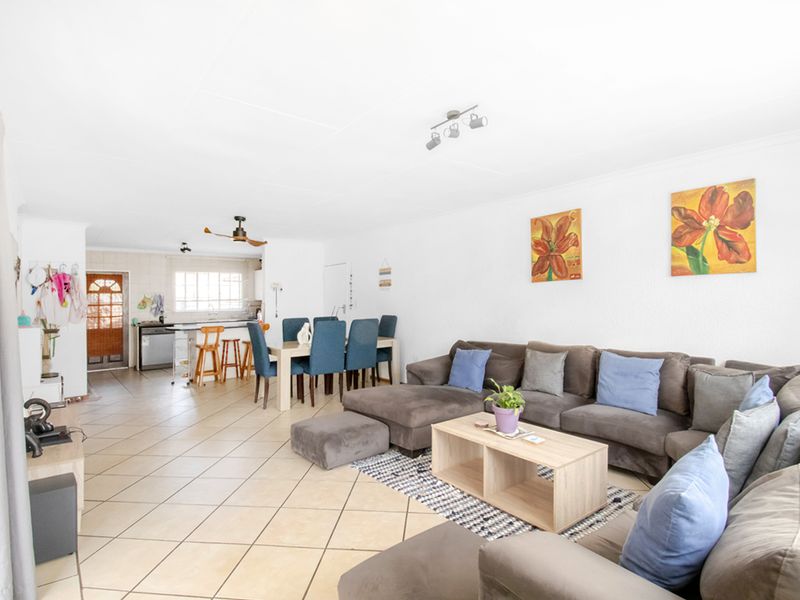 Spacious open-plan living and dining area featuring tiled flooring, a functional kitchen with island, and neutral finishes throughout.