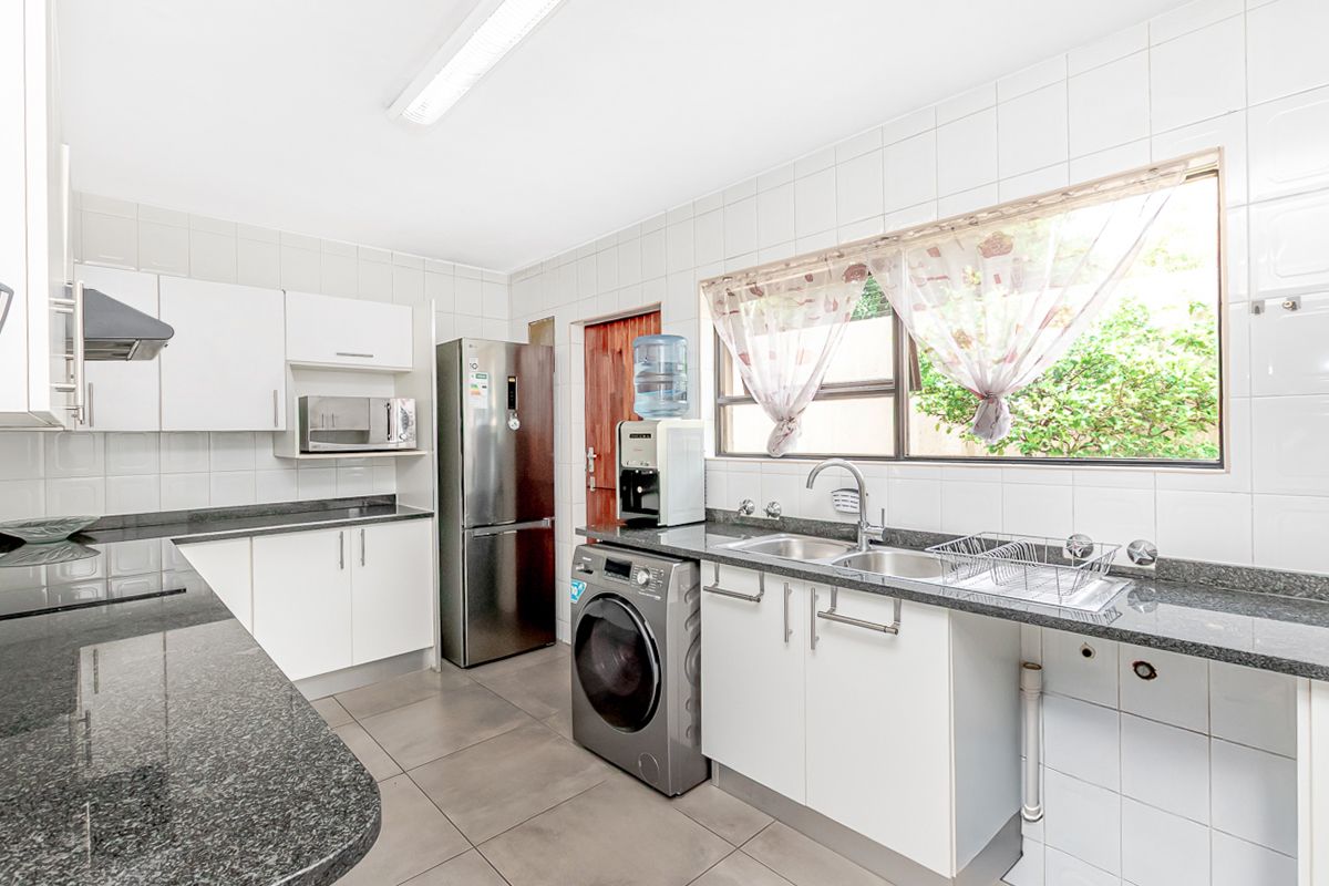 A functional kitchen featuring granite countertops, white cabinetry, tiled backsplash, and integrated appliances, offering a clean and practical workspace.
