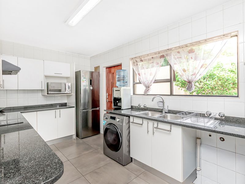 A functional kitchen featuring granite countertops, white cabinetry, tiled backsplash, and integrated appliances, offering a clean and practical workspace.