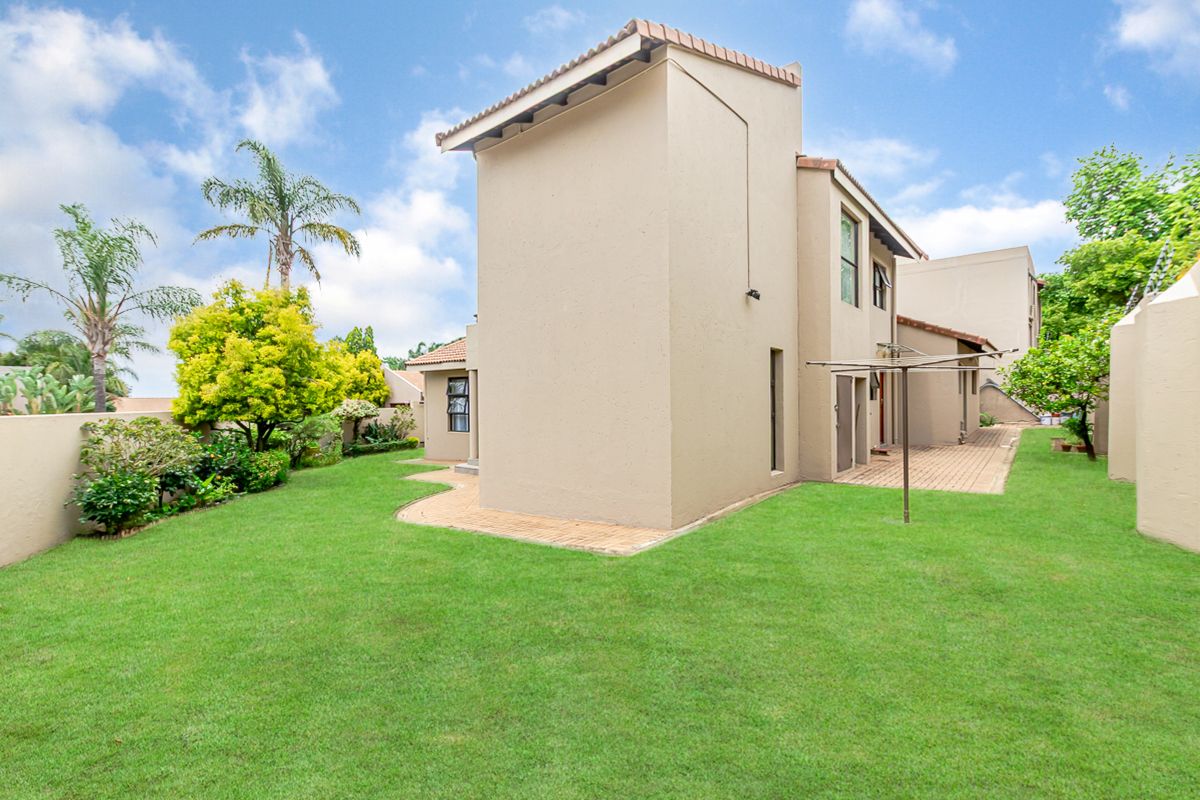 A well-maintained rear garden featuring a paved patio area, lush lawn, and secure boundary walls, providing a private outdoor space.