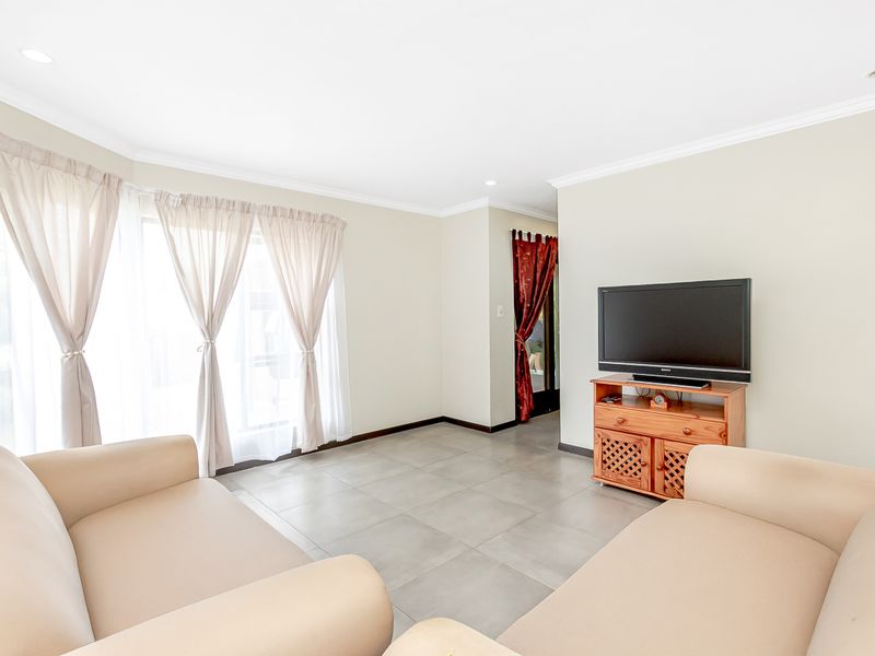 A bright living room featuring neutral tiled flooring, recessed downlighting, and a sliding glass door providing natural light.
