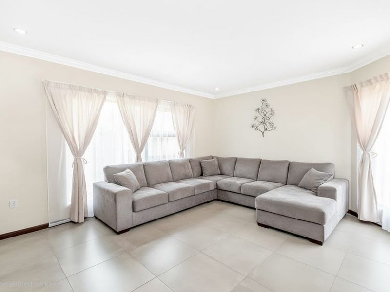 A bright and spacious living room featuring neutral tiled flooring, recessed downlighting, and elegant cornice detailing, creating a clean and inviting atmosphere.