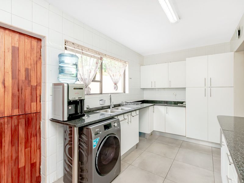 A functional kitchen featuring granite countertops, white cabinetry, tiled splashbacks, and tiled flooring, providing a clean and practical workspace.
