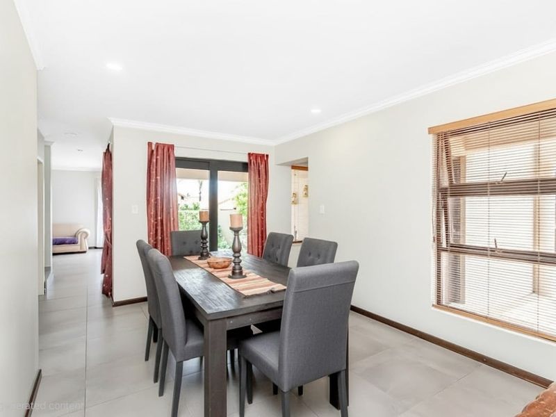 A bright dining room featuring neutral tiled flooring, cove cornicing, and a sliding glass door providing access to the exterior.