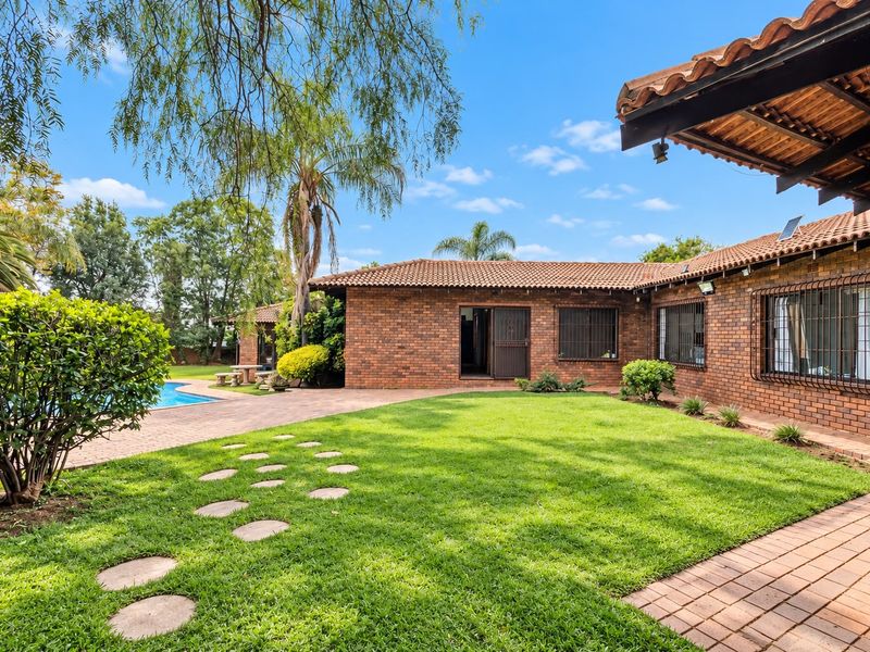 Spacious rear garden featuring a brick-built home, paved patio area, and a swimming pool, ideal for outdoor entertaining.