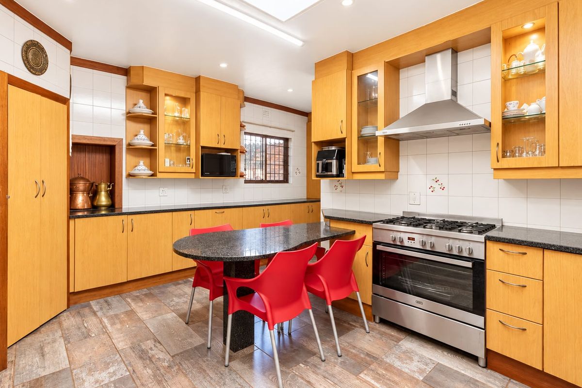 Spacious kitchen featuring warm wooden cabinetry, granite countertops, a stainless steel gas stove with extractor, and a bright skylight for natural illumination.